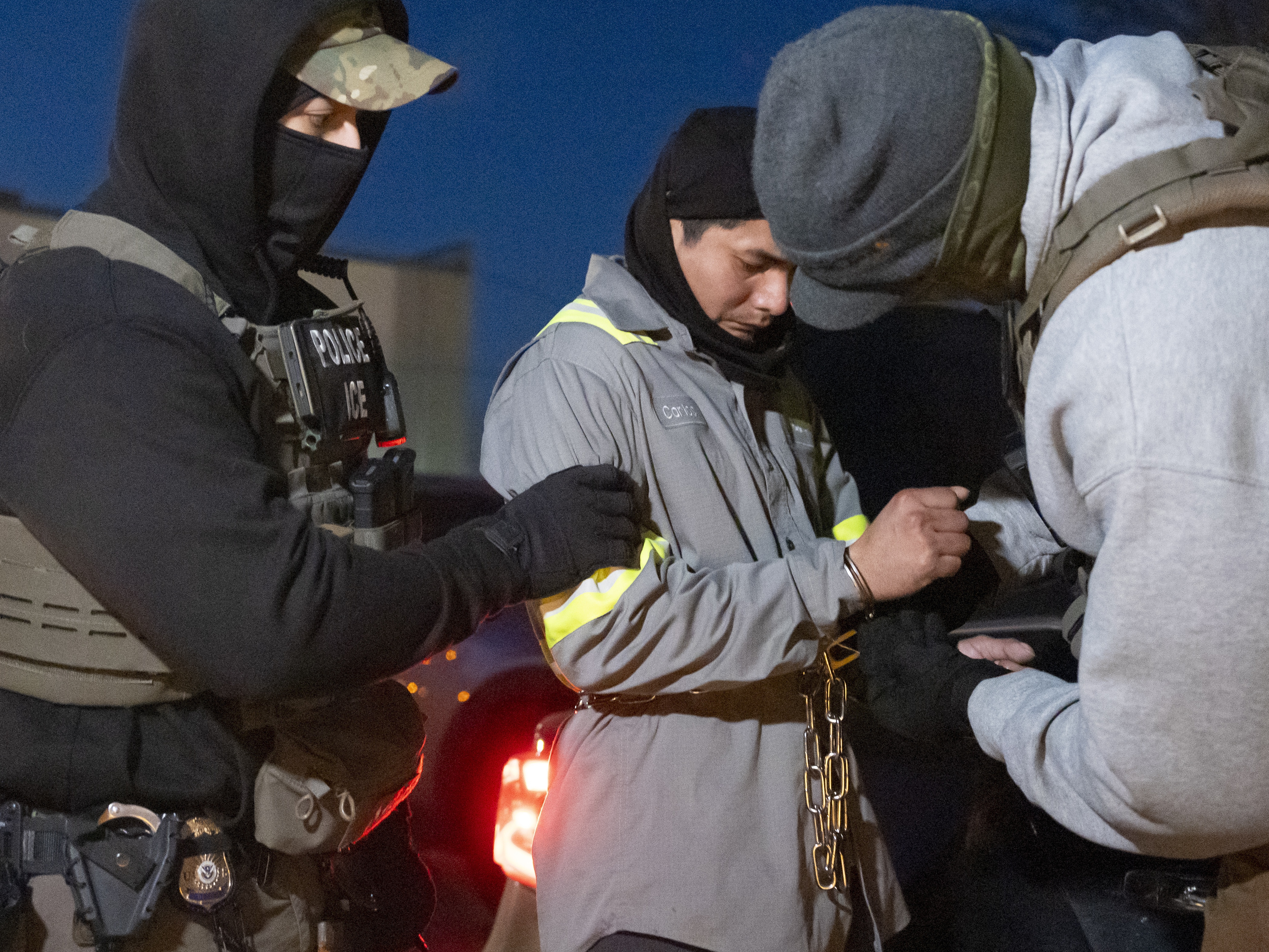 caption: U.S. Immigration and Customs Enforcement officers use a chain to more comfortably restrain a detained person using handcuffs positioned in front.