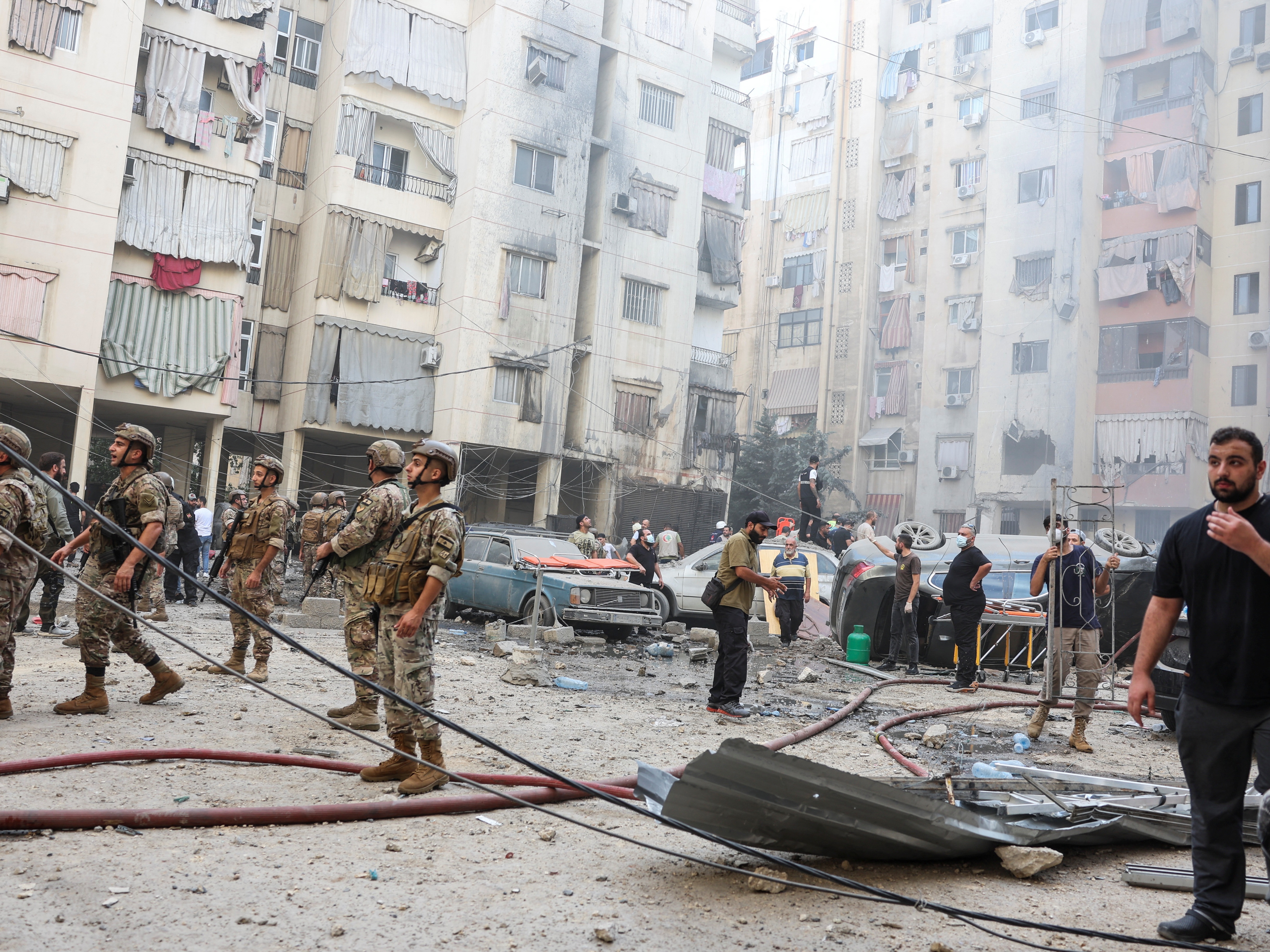 caption: People and members of the military inspect the site of an Israeli strike in the southern suburbs of Beirut, Lebanon, on Friday.