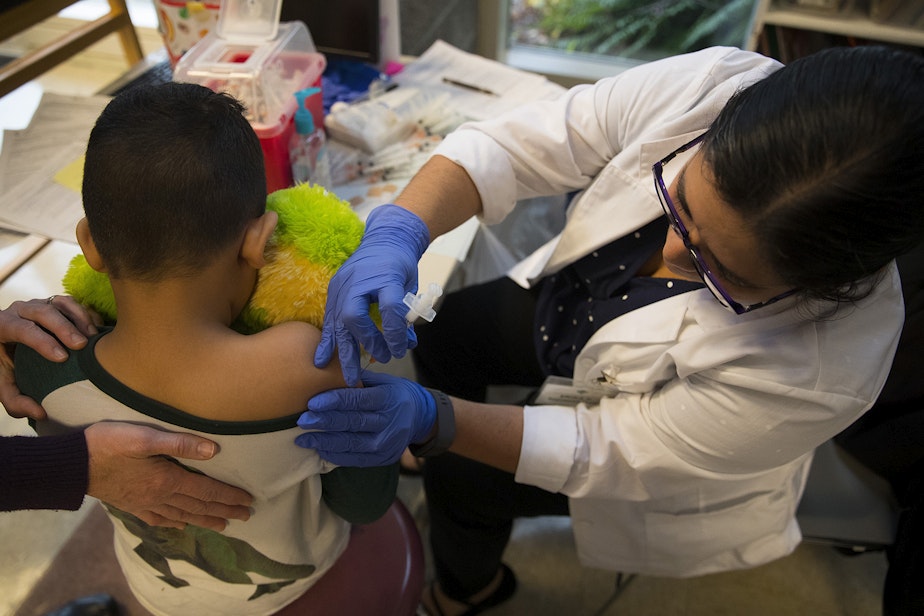 caption: Erika Sandoval, a nurse with the Seattle Visiting Nurse Association, gives kindergartener Aron Salinas Castellon a flu shot on Tuesday, October 22, 2019, at Concord International Elementary School in Seattle. 