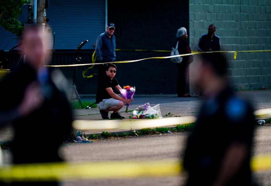 caption: A person places flowers outside the scene of a shooting at a supermarket in Buffalo, N.Y., Sunday, May 15, 2022. 