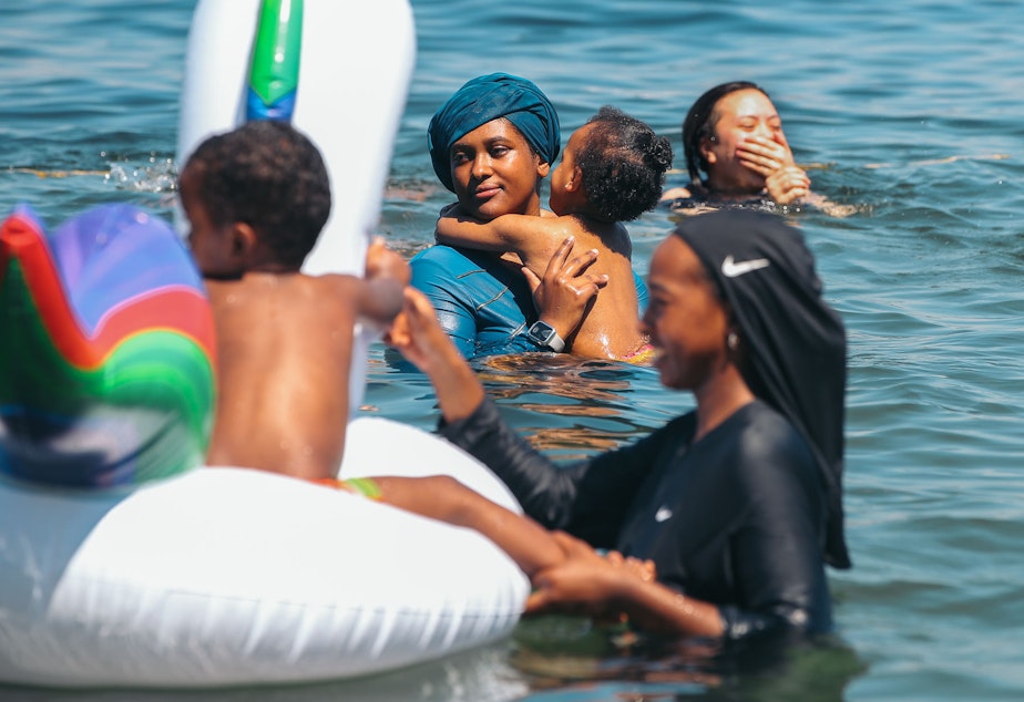 caption: Amane Robale, center, holds her daughter Rumaisa, 1, and her sister Oromiya Robale, foreground, holds her brother Yusuf, 2, on a float as they cool off in Lake Washington at Mt. Baker Beach, Monday, June 28. The National Weather Service recorded 108 degrees in SeaTac on Monday, setting an all-time record for the area.