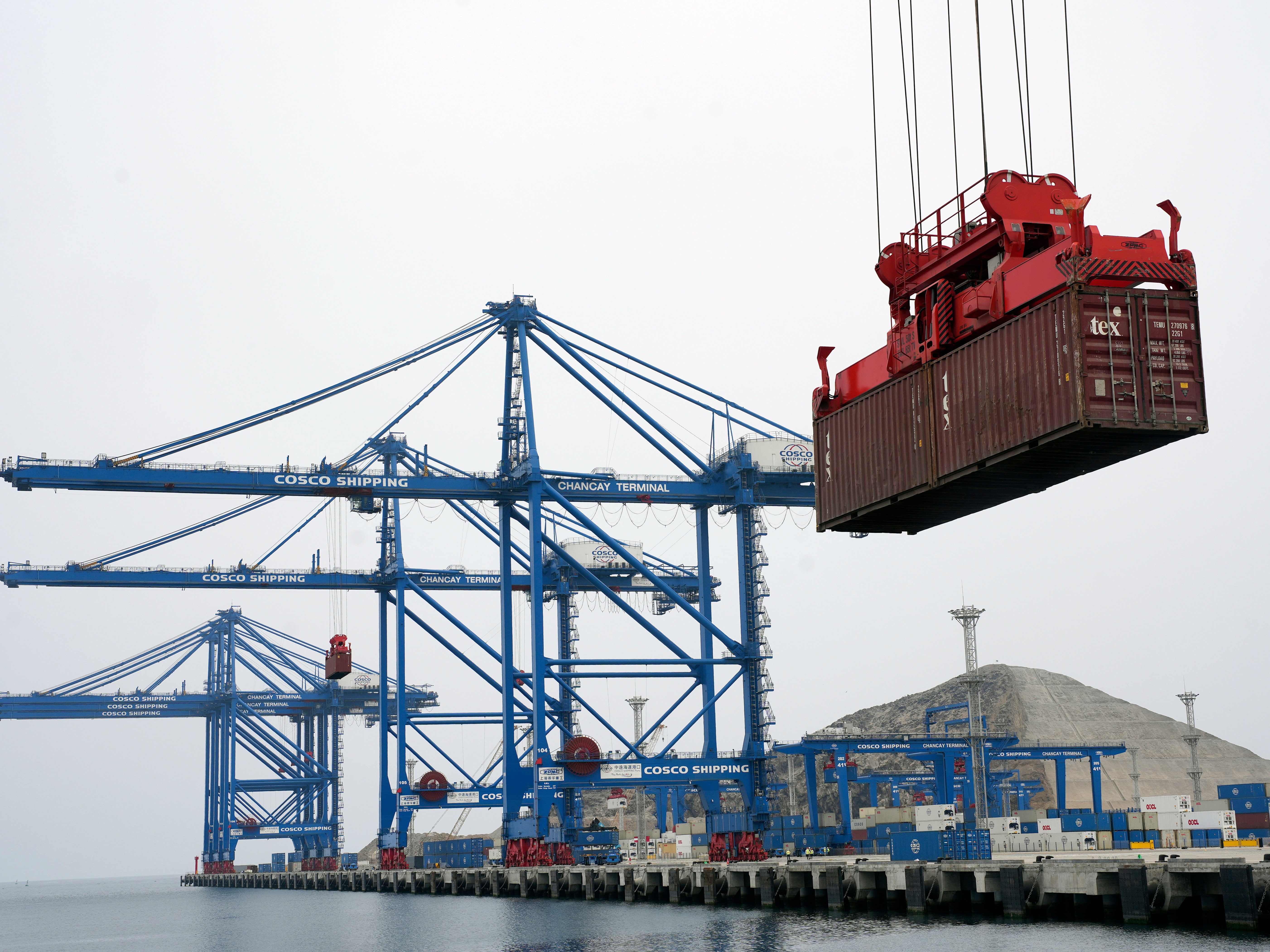 caption: A container is lifted by a crane backdropped by the construction of the Chinese-funded port, in Chancay, Peru, Oct. 29, 2024.