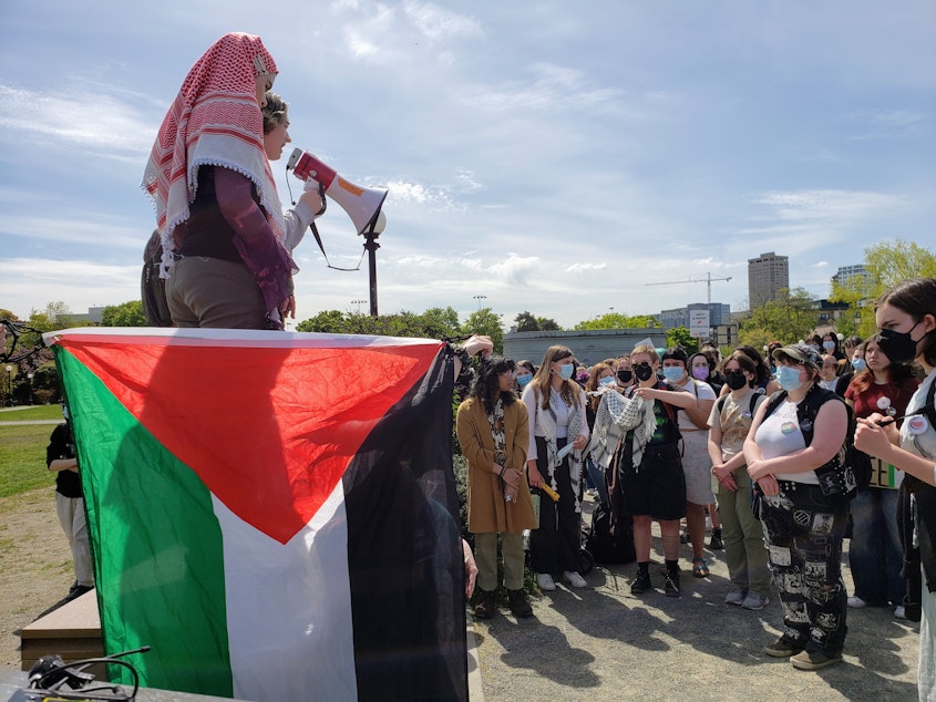 caption: Maysun Dawahare stands in front of a Palestinian flag at a protest at Cal Anderson Park on Tuesday, April 23, 2024.