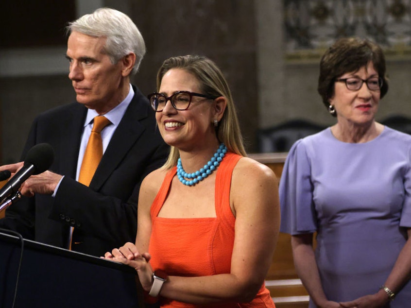 caption: Sen. Rob Portman, R-Ohio (left) and Sen. Kyrsten Sinema, D-Ariz., answer questions from the press as Sen. Susan Collins, R-Maine, looks on during a news conference about the bipartisan infrastructure deal on July 28.