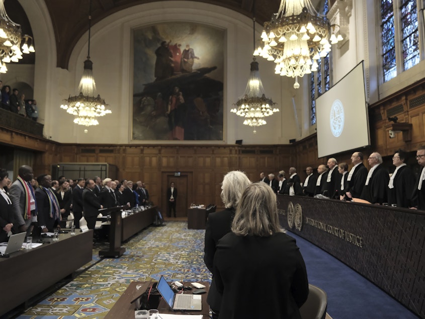 caption: Judges and parties stand up during a hearing at the International Court of Justice in The Hague, Netherlands, Friday. The United Nations' court opened hearings Thursday into South Africa's allegation that Israel's war with Hamas amounts to genocide against Palestinians, a claim that Israel strongly denies.