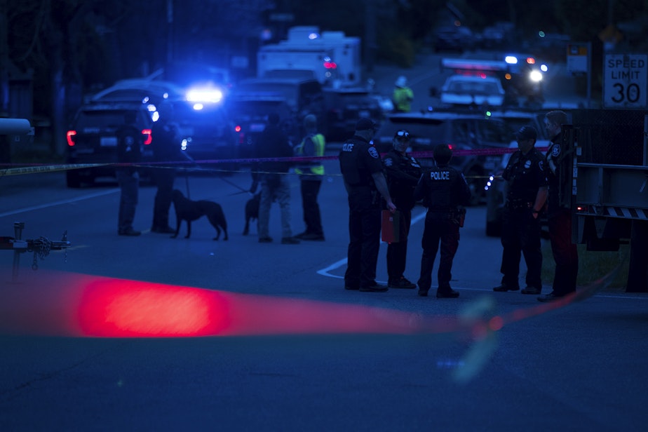 caption: Police investigate the scene of a fatal carjacking and shooting on Wednesday, March 27, 2019, at the intersection of 120th Street and Sandpoint Way Northeast in Seattle.