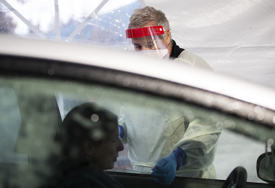 caption: Mark Radford, a paramedic with King County Medic One, administers a Covid-19 test on Wednesday, November 18, 2020, in the parking lot of the Weyerhaeuser King County Aquatic Center along Southwest Campus Drive in Federal Way. 