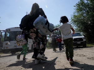 caption: A migrant family from Venezuela walks to a Border Patrol transport vehicle after they and other migrants crossed the U.S.-Mexico border and turned themselves in June 16, 2021, in Del Rio, Texas.