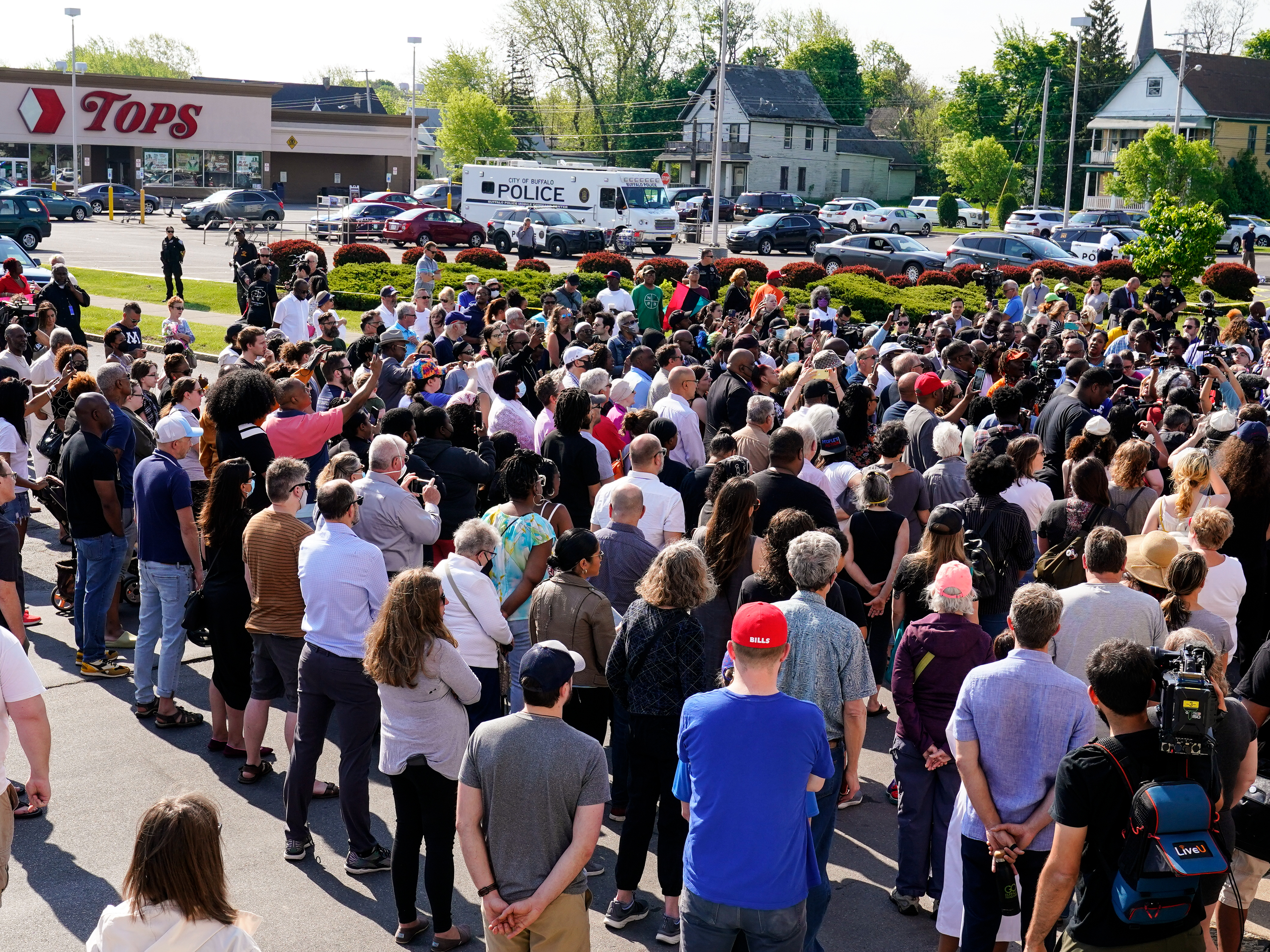 caption: People gather outside the scene of a shooting at a supermarket in Buffalo, N.Y., Sunday, May 15, 2022.