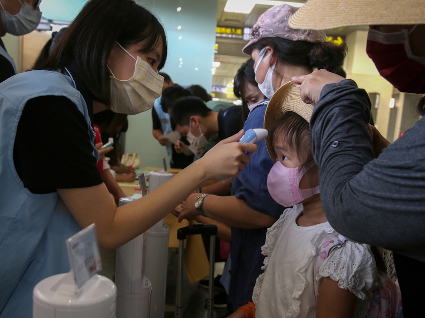 caption: Travel rules and regulations — and national lockdowns — have varied wildly, which gave SARS-CoV-2 lots of opportunities to spread. Above: A young traveler's temperature is checked at Taipei Songshan Airport in July 2020.