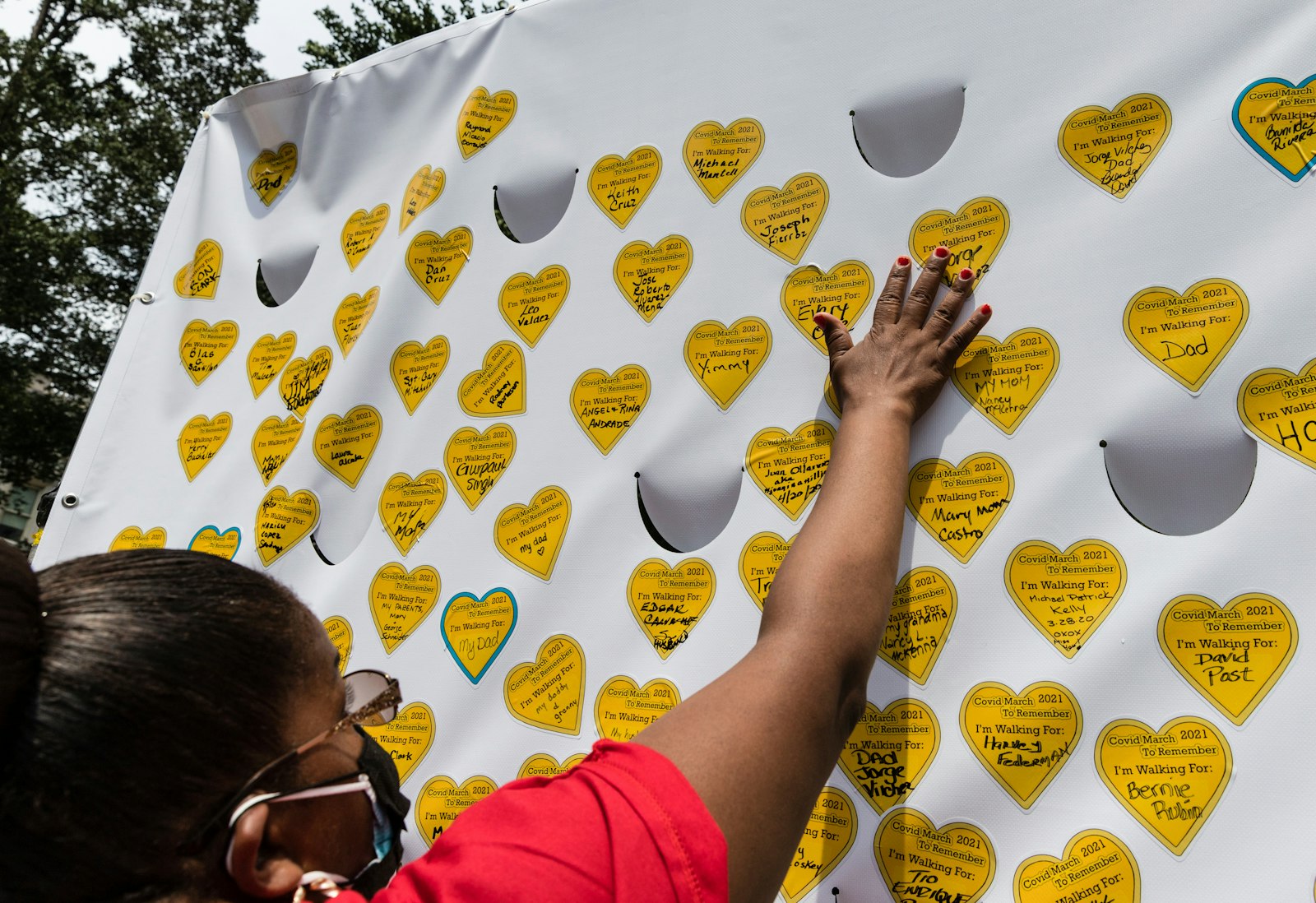 COVID-19 survivors gather in New York and place stickers representing lost relatives on a wall in remembrance of those who have died during the pandemic.
