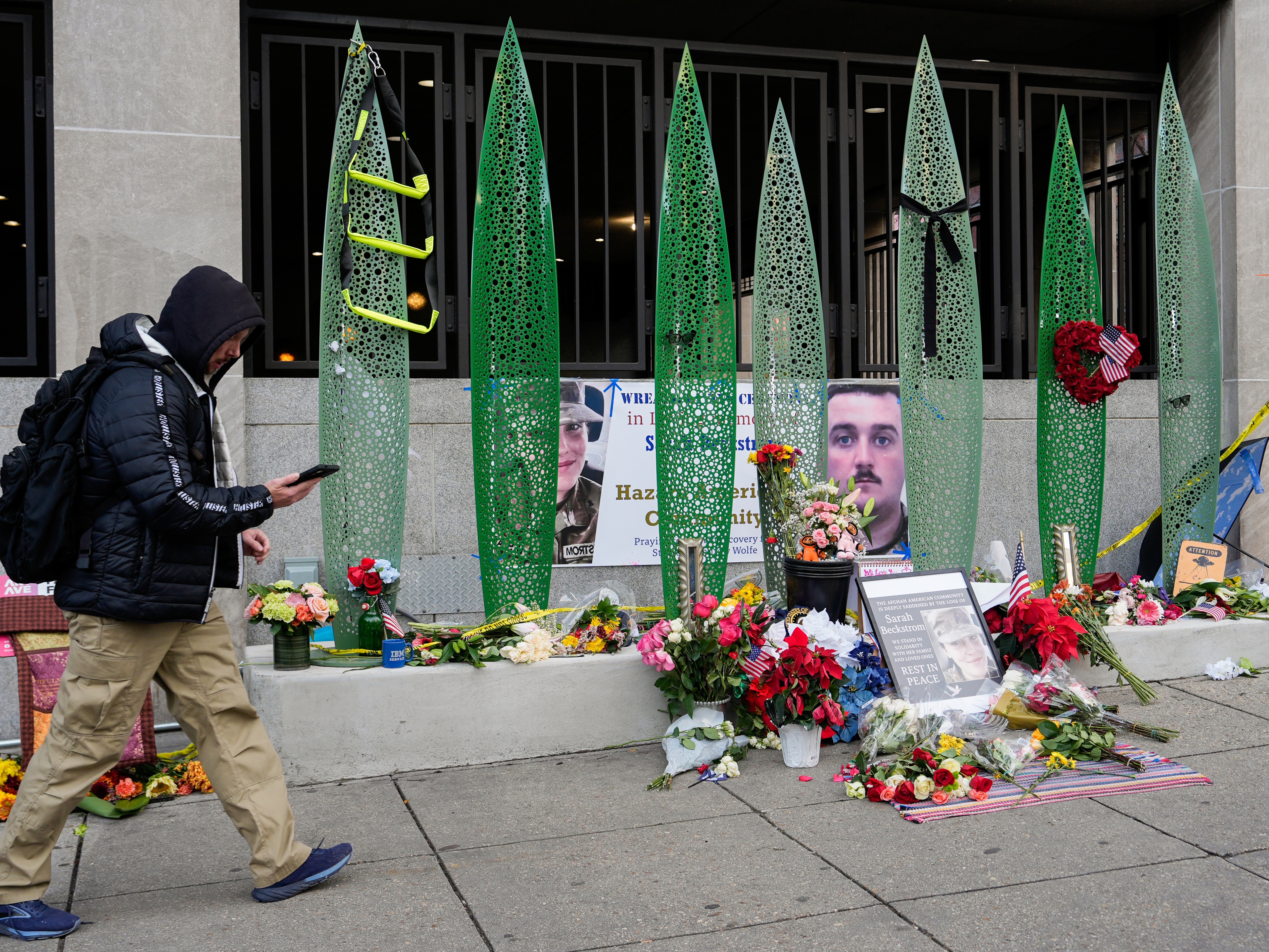 caption: A person walks past a makeshift memorial for U.S. Army Spc. Sarah Beckstrom and U.S. Air Force Staff Sgt. Andrew Wolfe outside of Farragut West Station, near the site where the two National Guard members were shot on Dec. 1 in Washington, D.C.