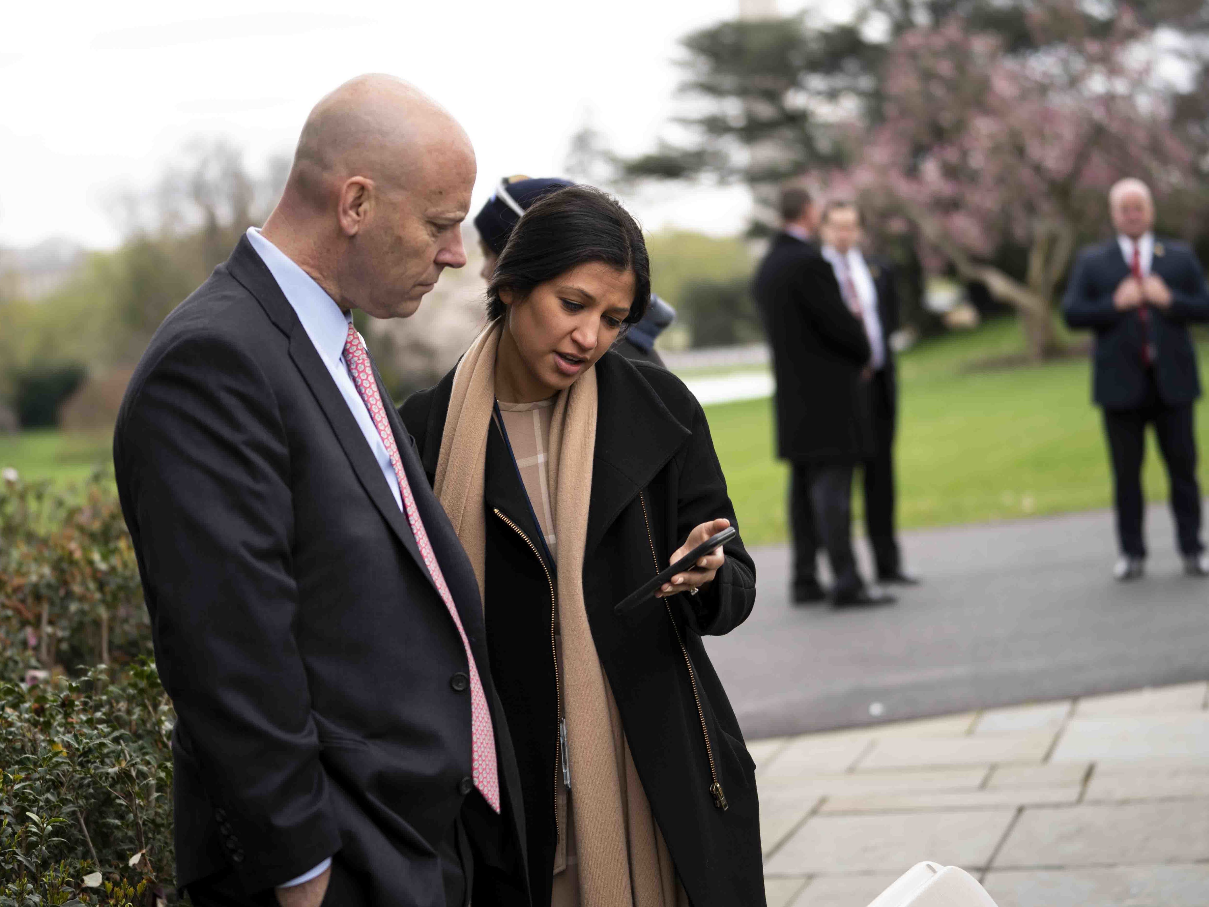 caption: Katie Miller, Vice President Pence's press secretary who has now tested positive for coronavirus, right, is seen during a Fox News virtual town hall in the Rose Garden of the White House in late March. At left is Marc Short, Pence's chief of staff.