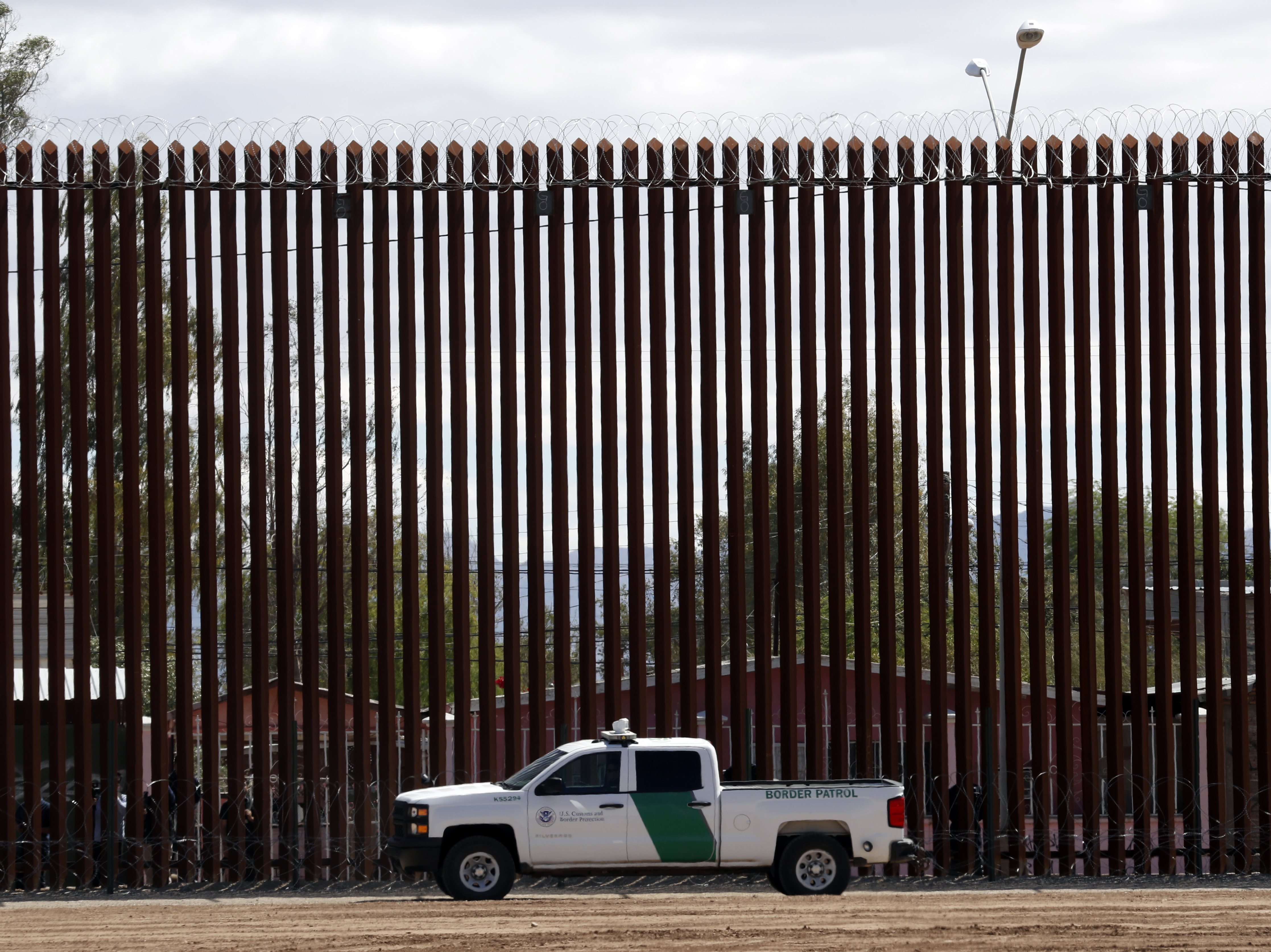 caption: A U.S. Customs and Border Protection vehicle sits near the wall as President Donald Trump visits a new section of the border wall with Mexico in El Centro, Calif., on April 5. This area is one where the Pentagon will spend more resources shifted away from military construction projects.
