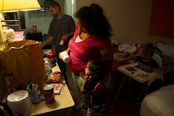 caption: Tynikki Arnold and Sean prepare ramen noodles for dinner for Vay, 5, and Messiah, 1, in their room at a Motel 6, on Friday, August 26, 2022. The family is staying at the motel after a fire tore through their apartment complex. 