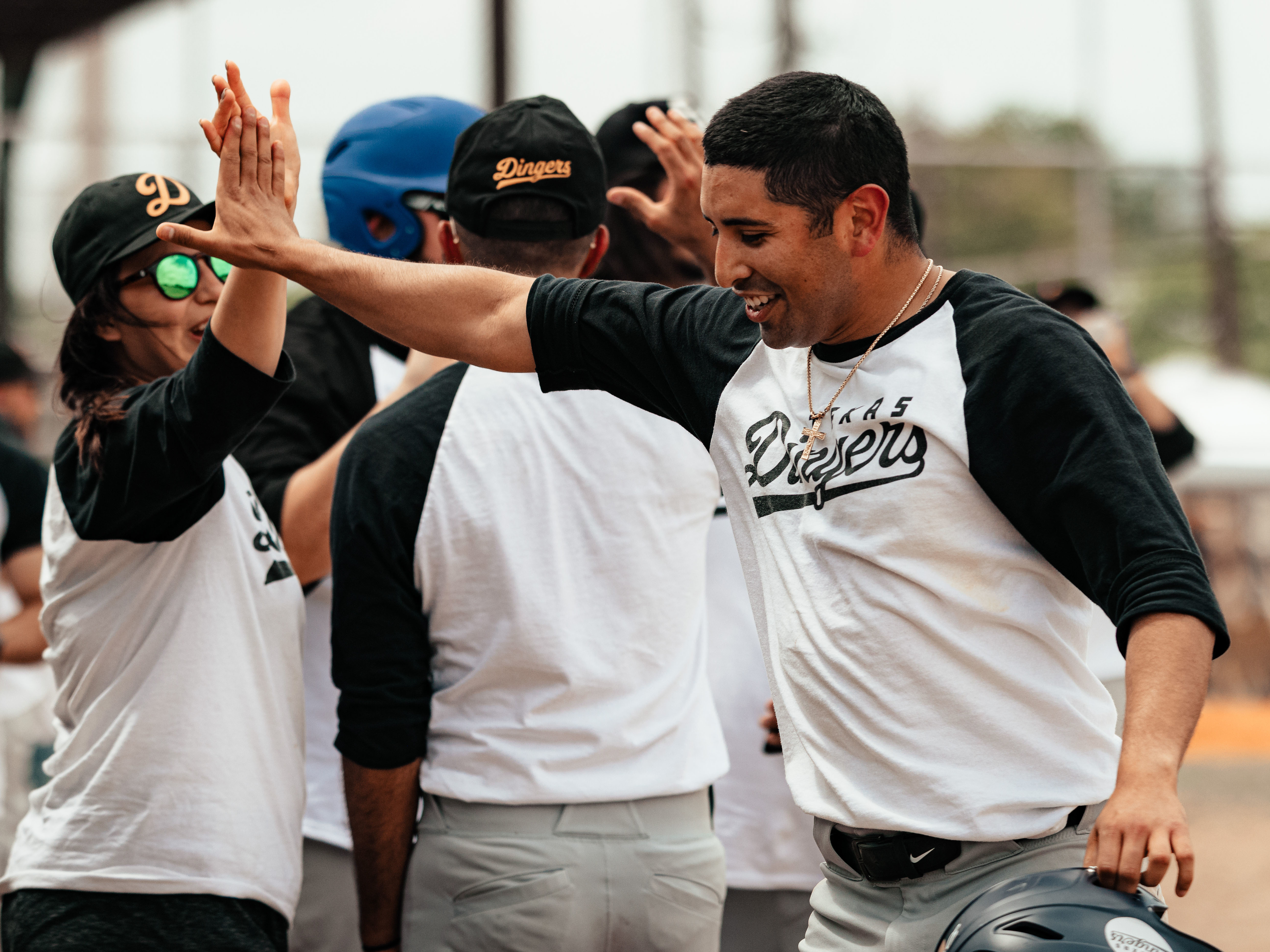 caption: The Dingers' Matthew Carrillo shares a high five with a teammate.