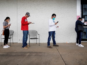 caption: People who lost their jobs wait in line to file for unemployment benefits at an Arkansas Workforce Center in Fayetteville, Ark., on April 6.