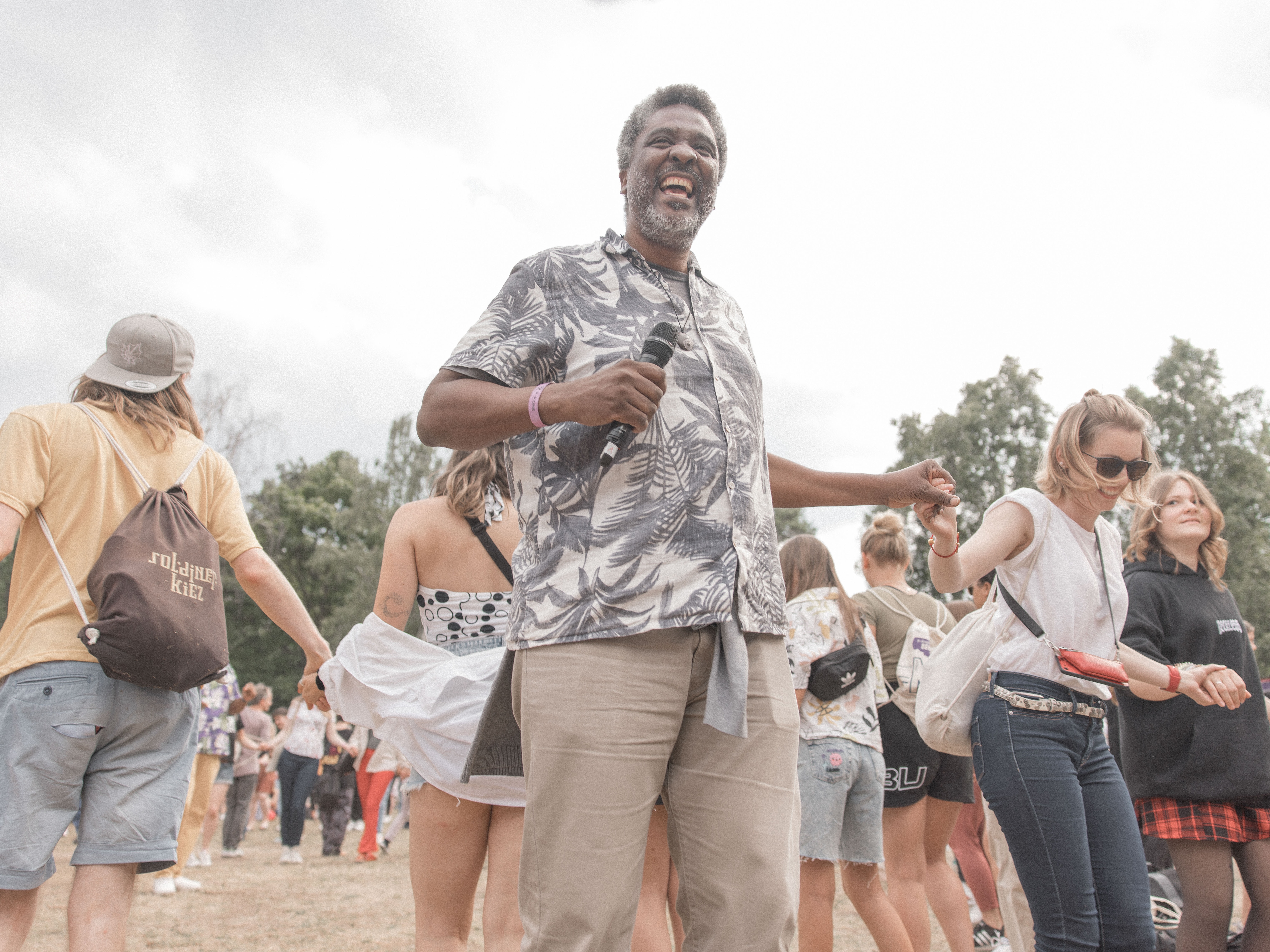 caption: Edgard Gouveia stages communal games to help people connect and solve problems. Dancing together is part of his process. Above: At a circle dance at a festival in Berlin, he asked participants to hug at least five other people. Many of them came up to him to thank and hug him, too.