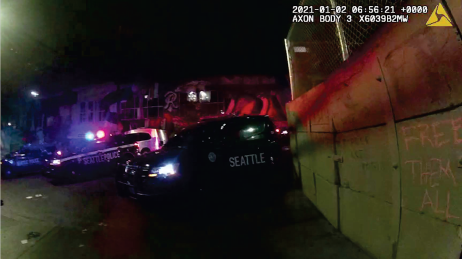 caption: Still image from the bodycam footage of a Seattle Police officer on Jan. 1, 2021, that shows the concrete barrier, some of the protesters' statements, and the police response.