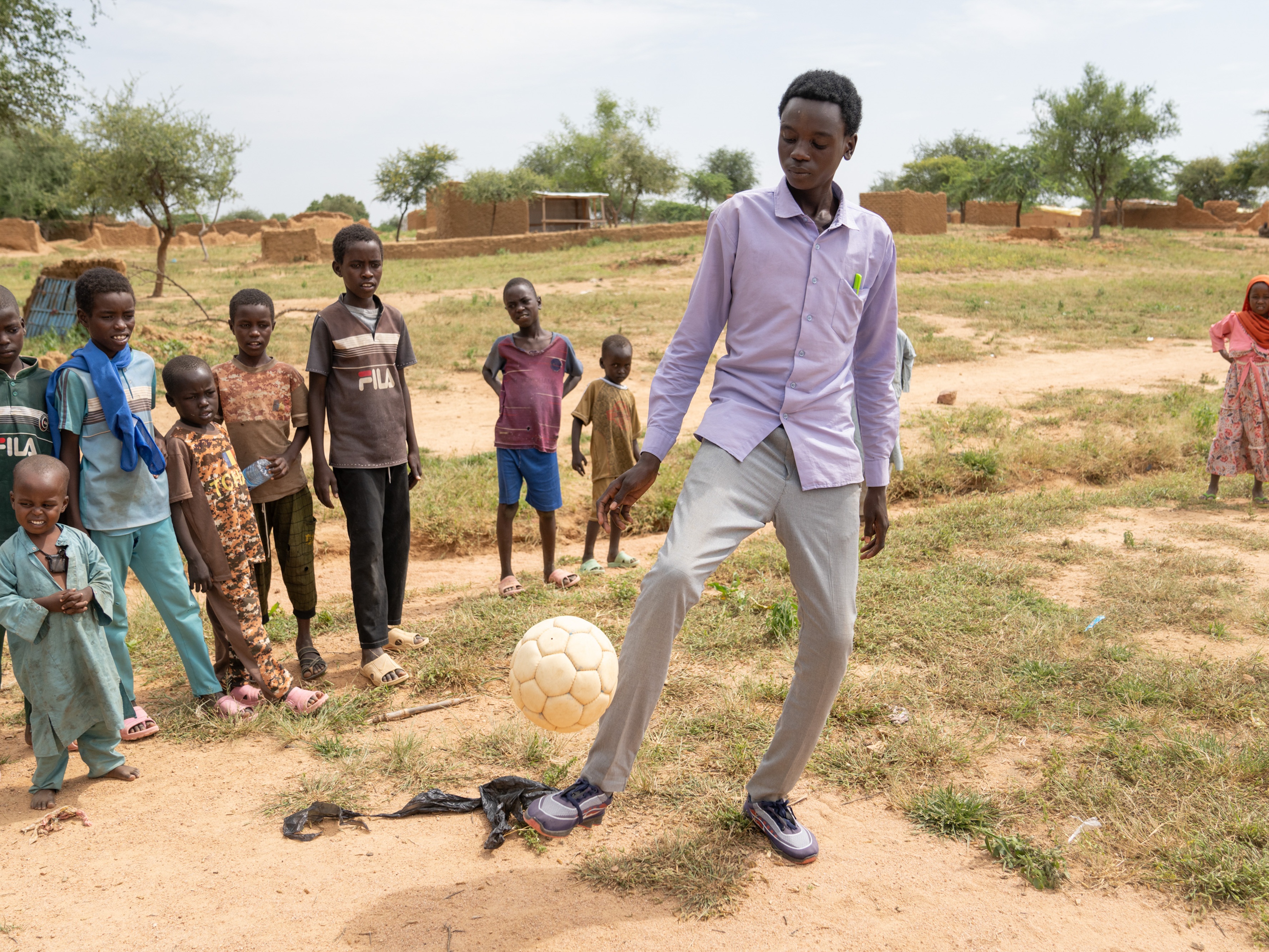 caption: Mahawat Zakaria Jouma is happy when he gets a chance to play soccer, but mostly he is busy taking care of his siblings, trying to earn money makeing bricks, and going to school.