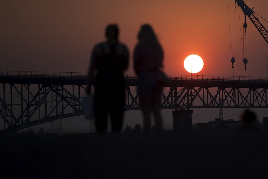 caption: People watch as the sun sets from Gas Works Park on Monday, July 30, 2018, in Seattle. 