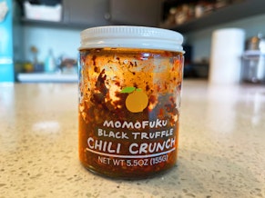 caption: A jar of Momofuku's black truffle chili crunch.