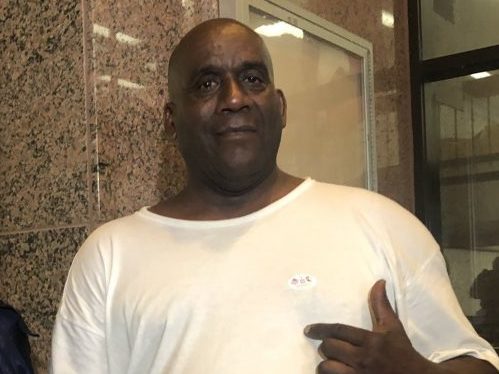 caption: Hervis Rogers points to his "I voted" sticker on Super Tuesday in 2020. This week he was arrested for allegedly voting while on parole, which is illegal in Texas.