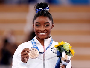 caption: Simone Biles poses with the bronze medal during the Women's Balance Beam Final medal ceremony on day eleven of the Tokyo 2020 Olympic Games on August 03, 2021.