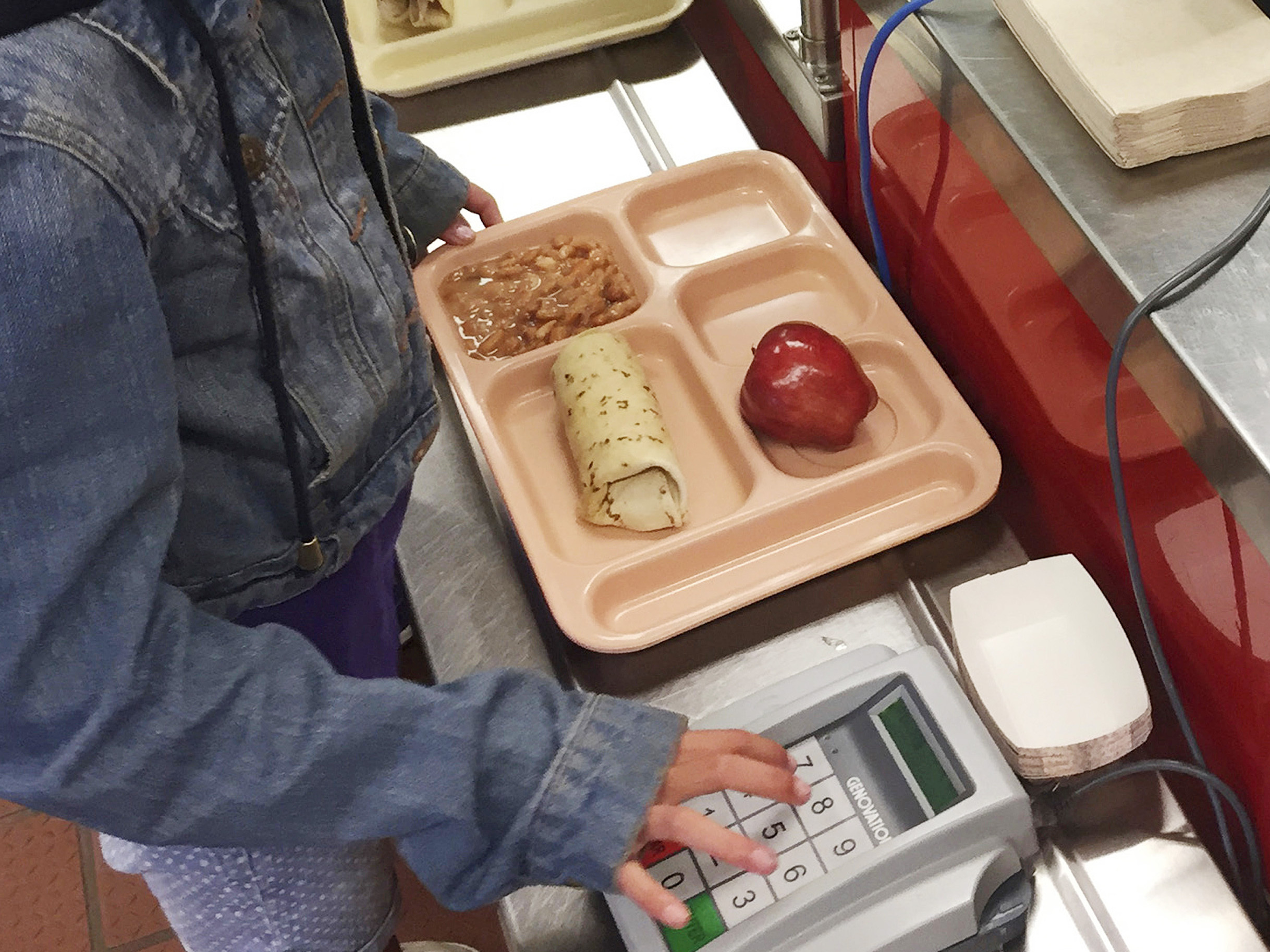 caption: A third-grader punches in her student identification to pay for a meal at Gonzales Community School in Santa Fe, N.M. During the pandemic, schools were able to offer free school meals to all children regardless of need. Now advocates want to make that policy permanent.