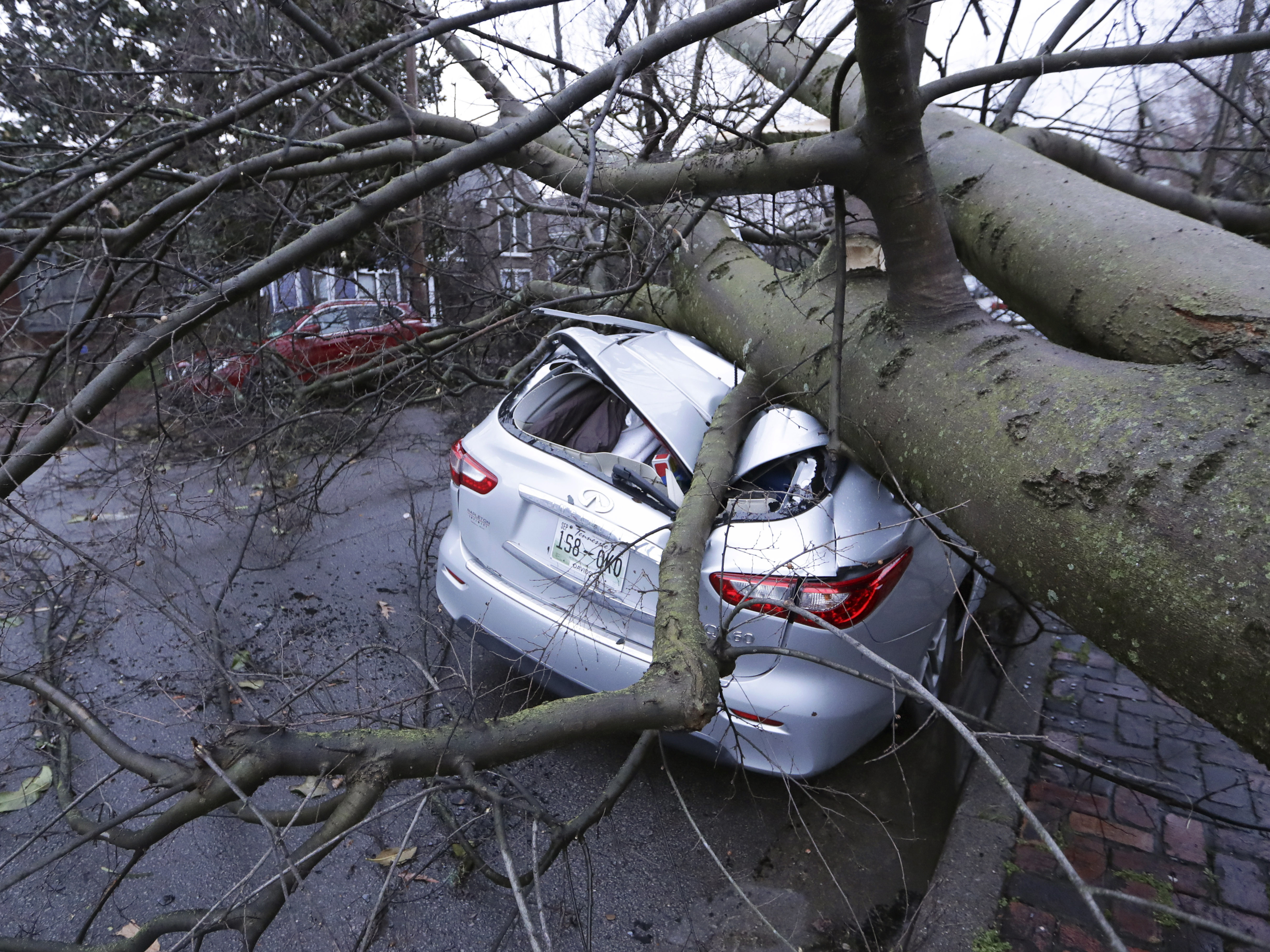 caption: A car crushed by a tree sits on a street after a tornado touched down Tuesday, in Nashville, Tenn.
