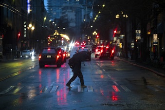 caption: A pedestrian crosses First Avenue with an umbrella on Tuesday, Dec. 5, 2023, in Seattle. An atmospheric river has hit Western Washington with winds, heavy rain, and possible flooding. 