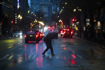 caption: A pedestrian crosses First Avenue with an umbrella on Tuesday, Dec. 5, 2023, in Seattle. An atmospheric river has hit Western Washington with winds, heavy rain, and possible flooding. 