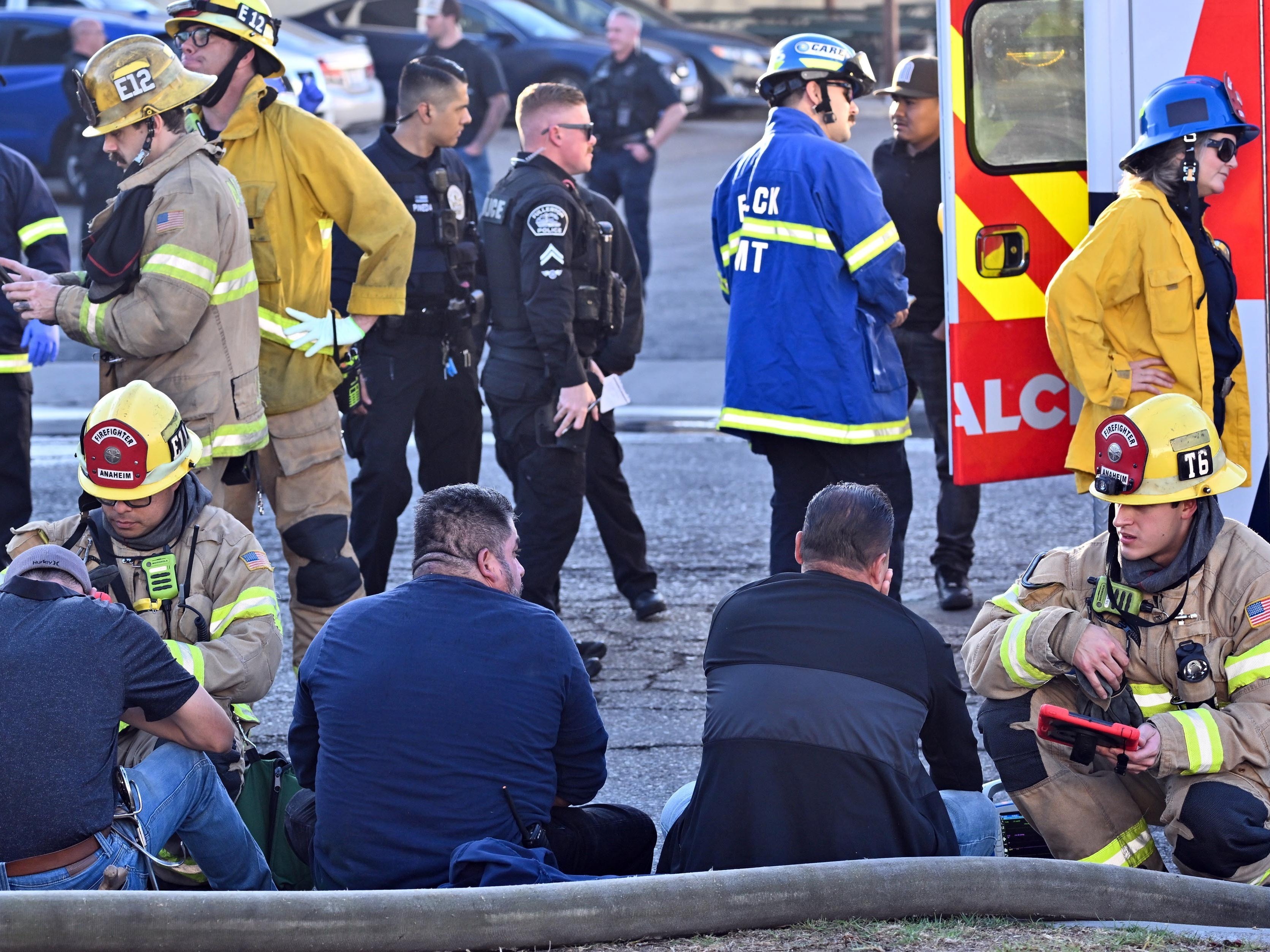 caption: Firefighters tend to people after a plane crashed through the roof of a building near Fullerton airport on Jan. 2, 2025, in Fullerton, Calif.