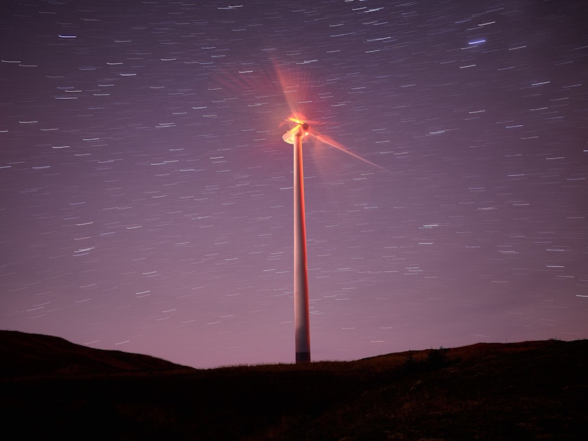 caption:  A red blinking light on a turbine at night.