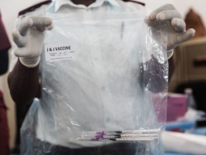 caption: A health care worker holds doses of J&J vaccines at the Gandhi Phoenix Settlement in Bhambayi township, South Africa, on Sept. 24. A study of the J&J booster shot in the country had promising results against the omicron variant.