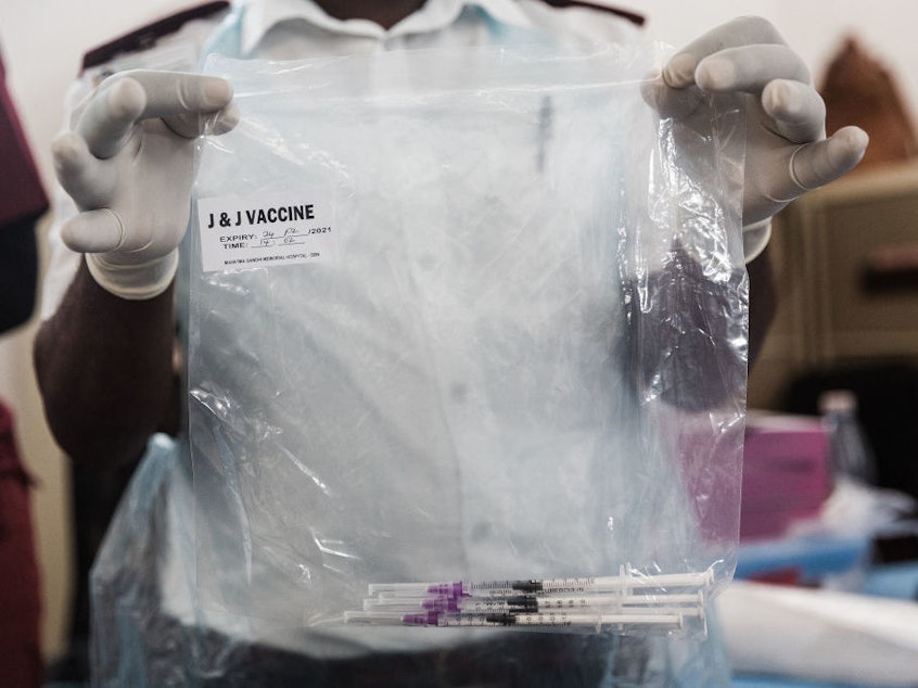 caption: A health care worker holds doses of J&J vaccines at the Gandhi Phoenix Settlement in Bhambayi township, South Africa, on Sept. 24. A study of the J&J booster shot in the country had promising results against the omicron variant.