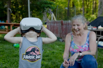 caption: Linda Munson's youngest grandson, Daniel Gomez, 2, tries on an Oculus headset in her yard in Berlin, Conn. Playing different virtual reality games has become her family's regular Sunday activity, Munson said.