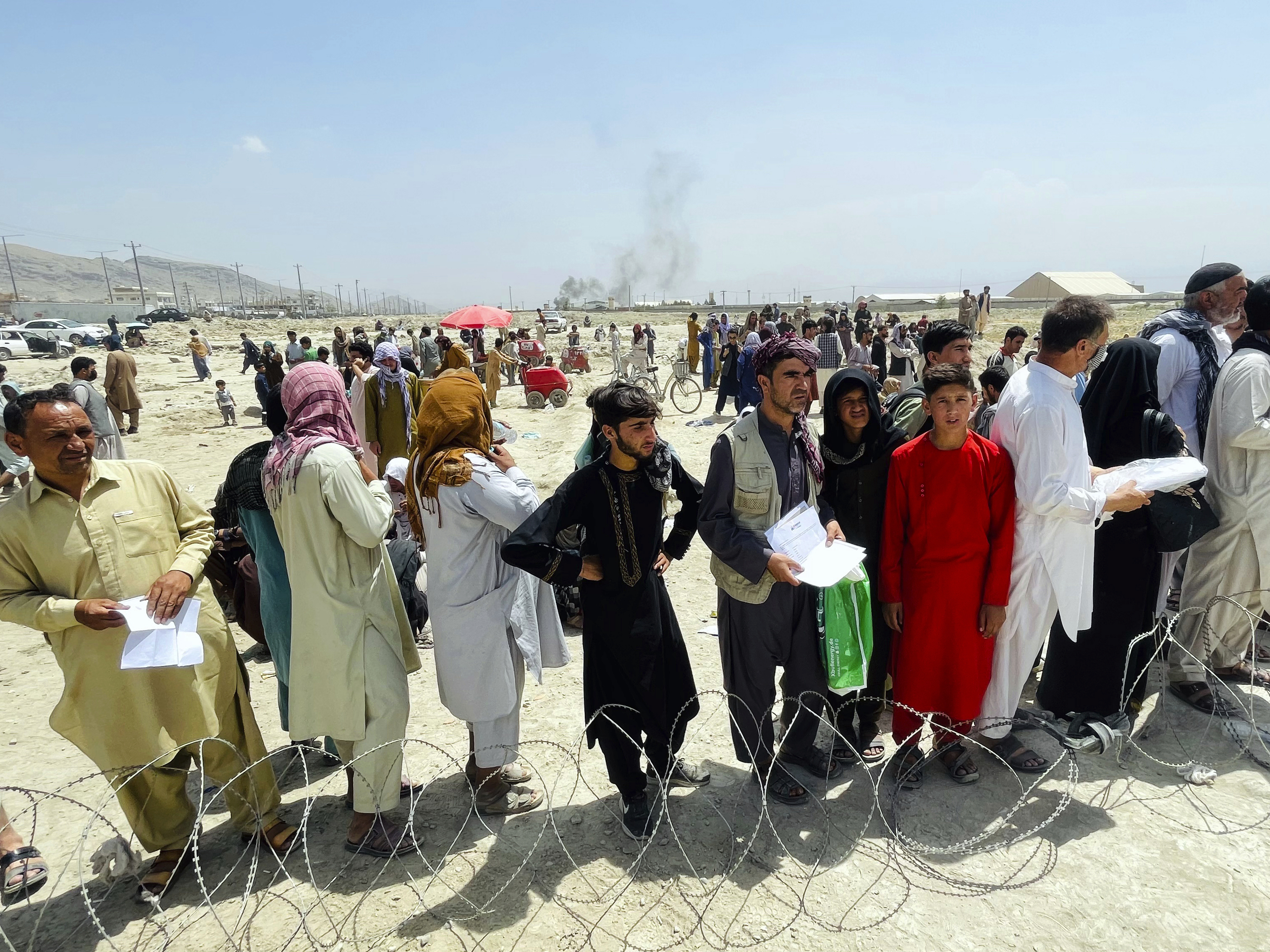 caption: Hundreds of people gather outside the international airport in Kabul, Afghanistan on Tuesday.