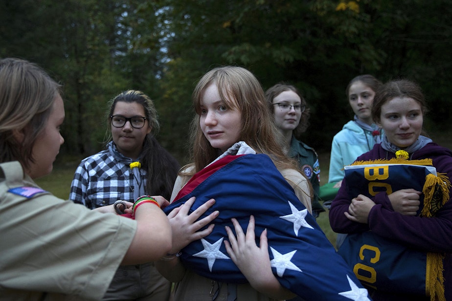 caption: Abigail Matthews, 13, has help from Moriko Peterson, 13, left, after a flag ceremony during the Boy Scouts of America Bootcamp for girls on Saturday, October 6, 2018, at Camp Thunderbird in Olympia. 