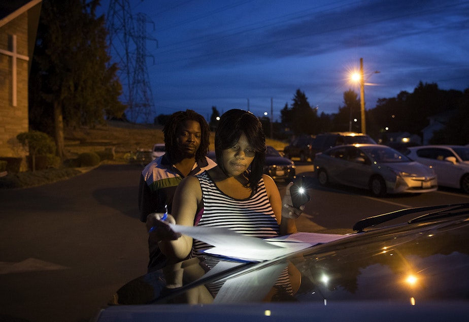 caption: Tiffany Hicks signs a lease for a three bedroom apartment in Auburn in the parking lot of Seattle Chinese Alliance Church on Friday, September 15, 2017, in Beacon Hill. 