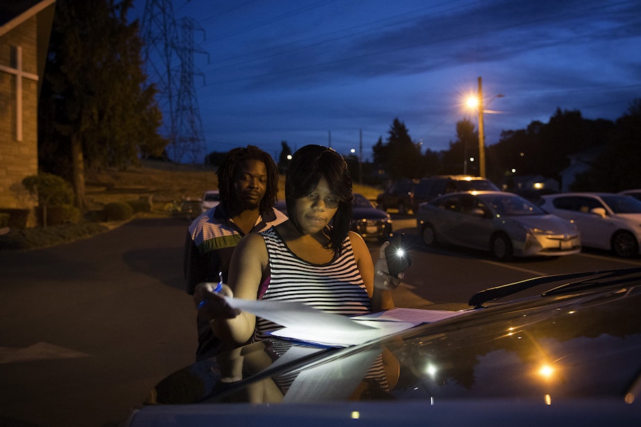caption: Tiffany Hicks signs a lease for a three bedroom apartment in Auburn in the parking lot of Seattle Chinese Alliance Church on Friday, September 15, 2017, in Beacon Hill. 