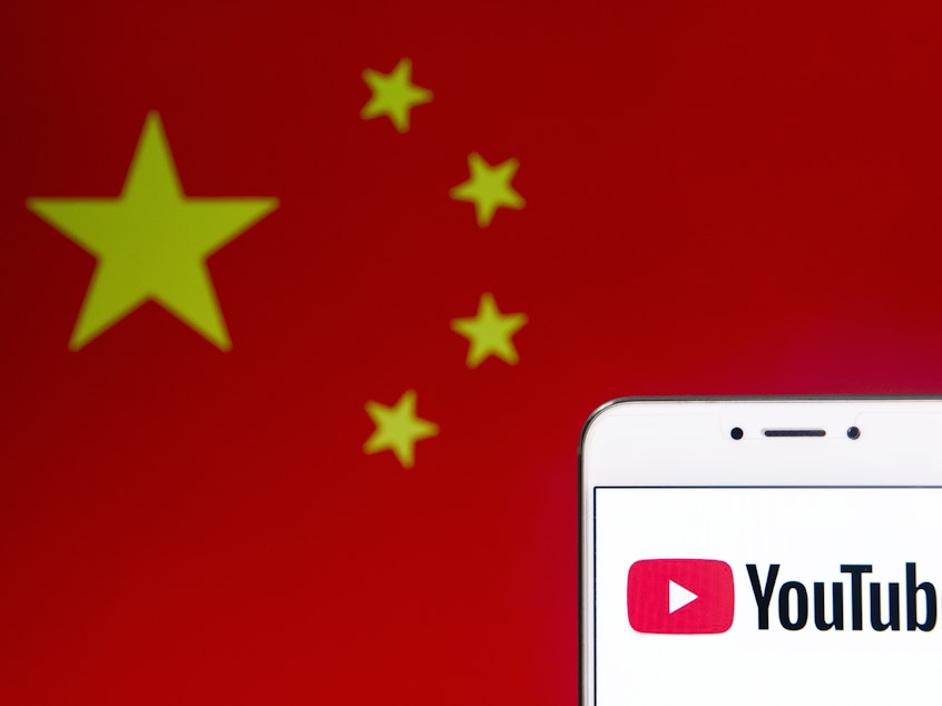 caption: An illustration of the video-sharing website Youtube logo and an Android mobile device with People's Republic of China flag in the background.
