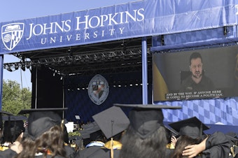 caption: Ukrainian President Volodymyr Zelenskyy addresses the graduating class of Johns Hopkins University via livestream from Ukraine on Thursday in Baltimore.