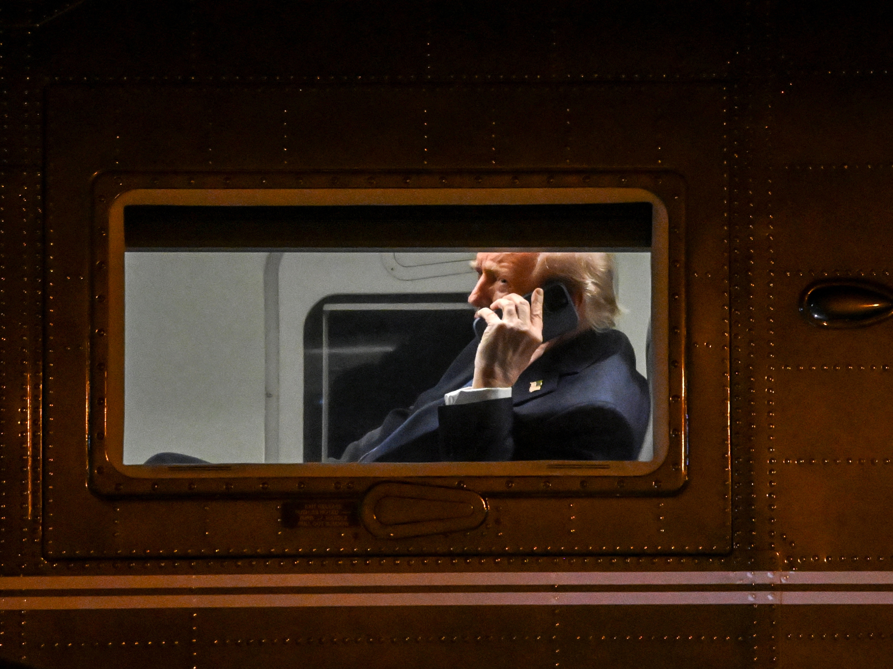 caption: President Trump uses a cell phone aboard his Marine One helicopter in Leesburg, Va., on April 24, 2025.