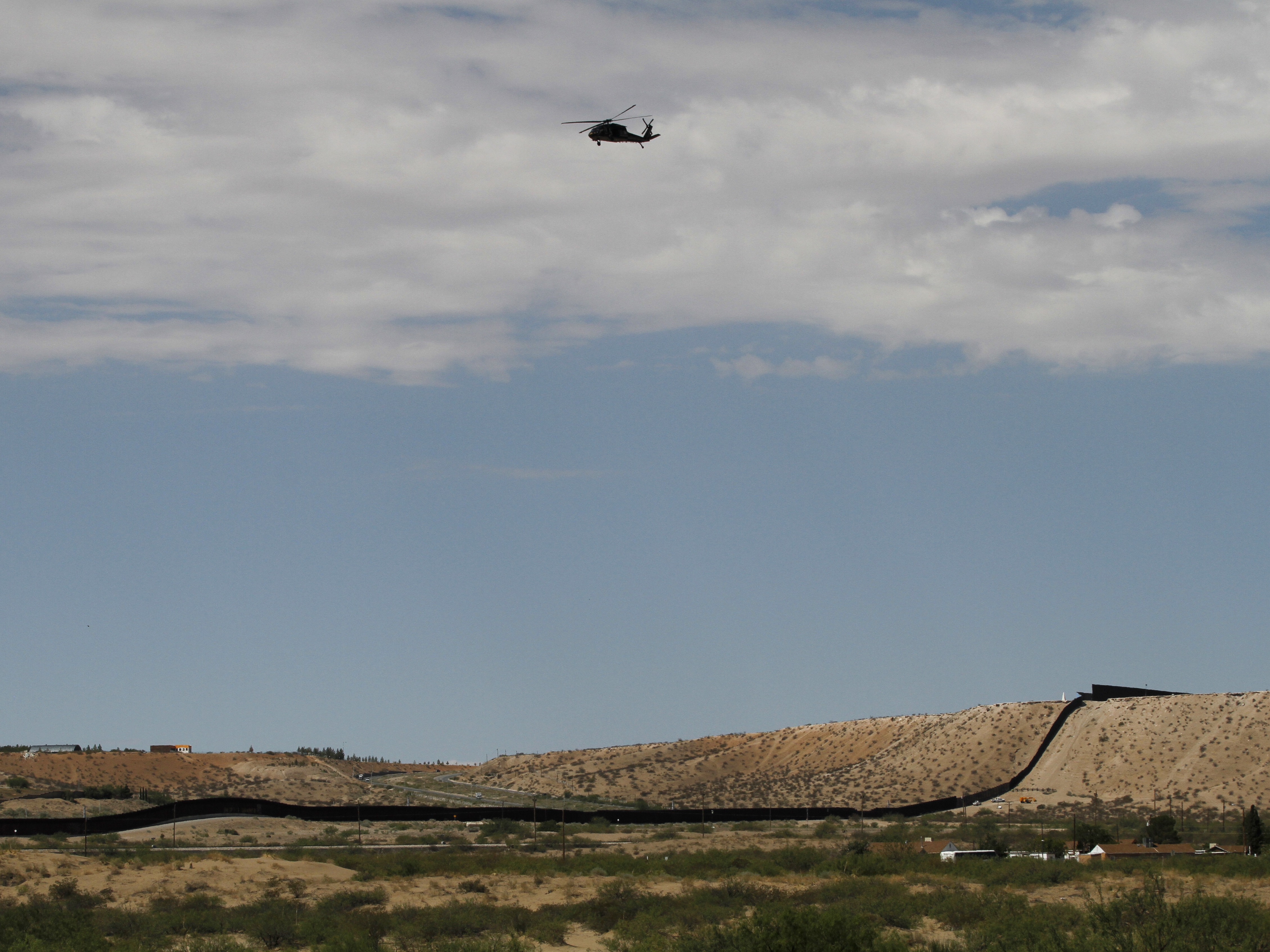 caption: A surveillance helicopter traces a line in the sky above the Southwest border with Mexico at Sunland Park, N.M., Thursday, Aug. 22, 2024.