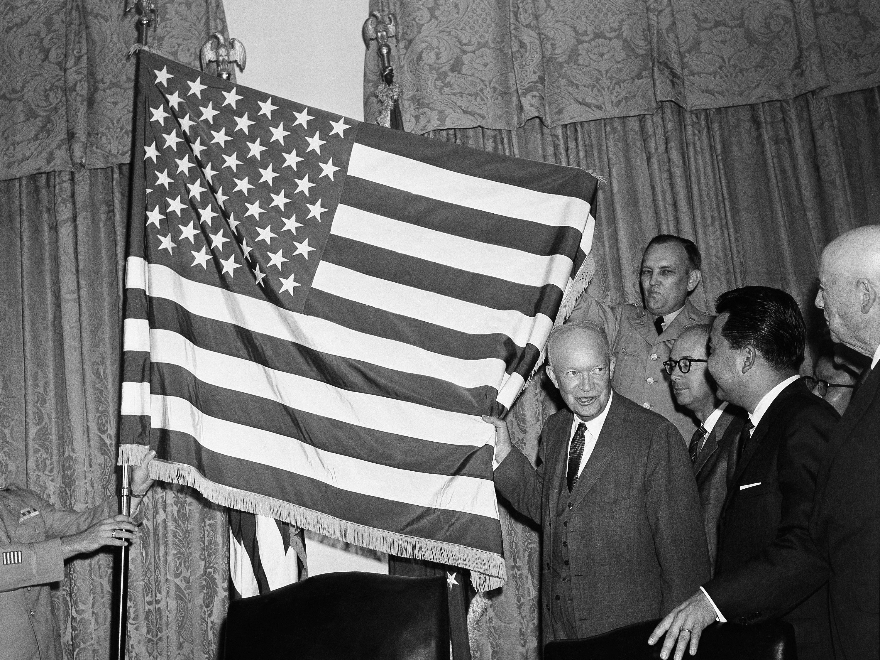 caption: President Dwight Eisenhower helps unfurl the new 50-star flag on Aug. 21, 1959 after signing a proclamation making Hawaii the 50th state of the union. At right is Daniel K. Inouye, Democratic congressman-elect from Hawaii.