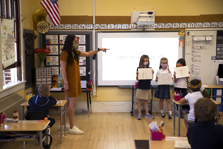 caption: Kate Ford, a teacher at Villa Academy, teaches first-grade students about vowels on Tuesday, April 20, 2021, at the school in Seattle.