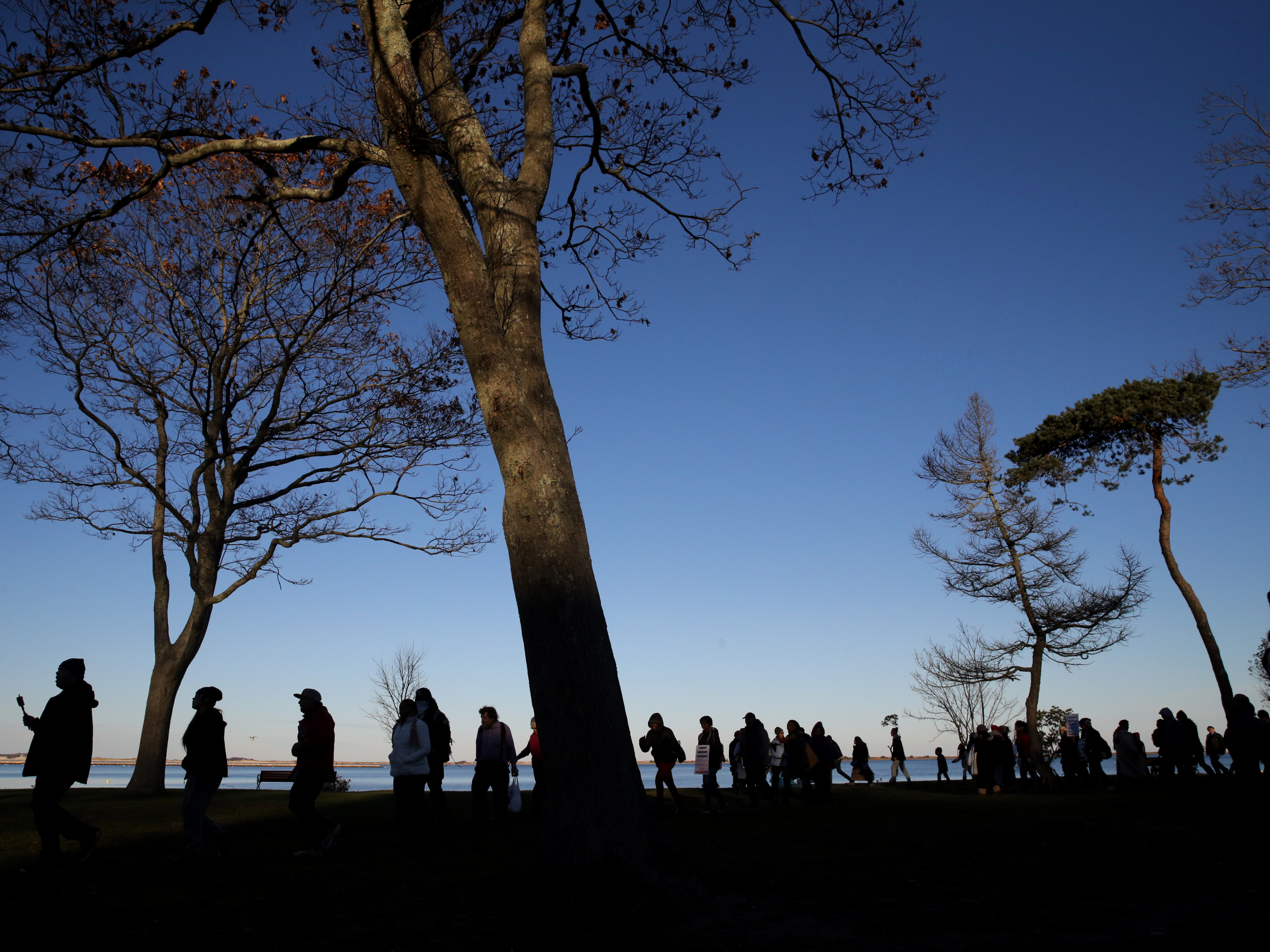 caption: Marchers perform a Stomp Dance in Pilgrim Memorial State Park during the 48th National Day of Mourning in Plymouth, Mass., on Nov 23, 2017. Since 1970, Indigenous people have gathered at noon on Cole's Hill in Plymouth to commemorate a National Day of Mourning on Thanksgiving.