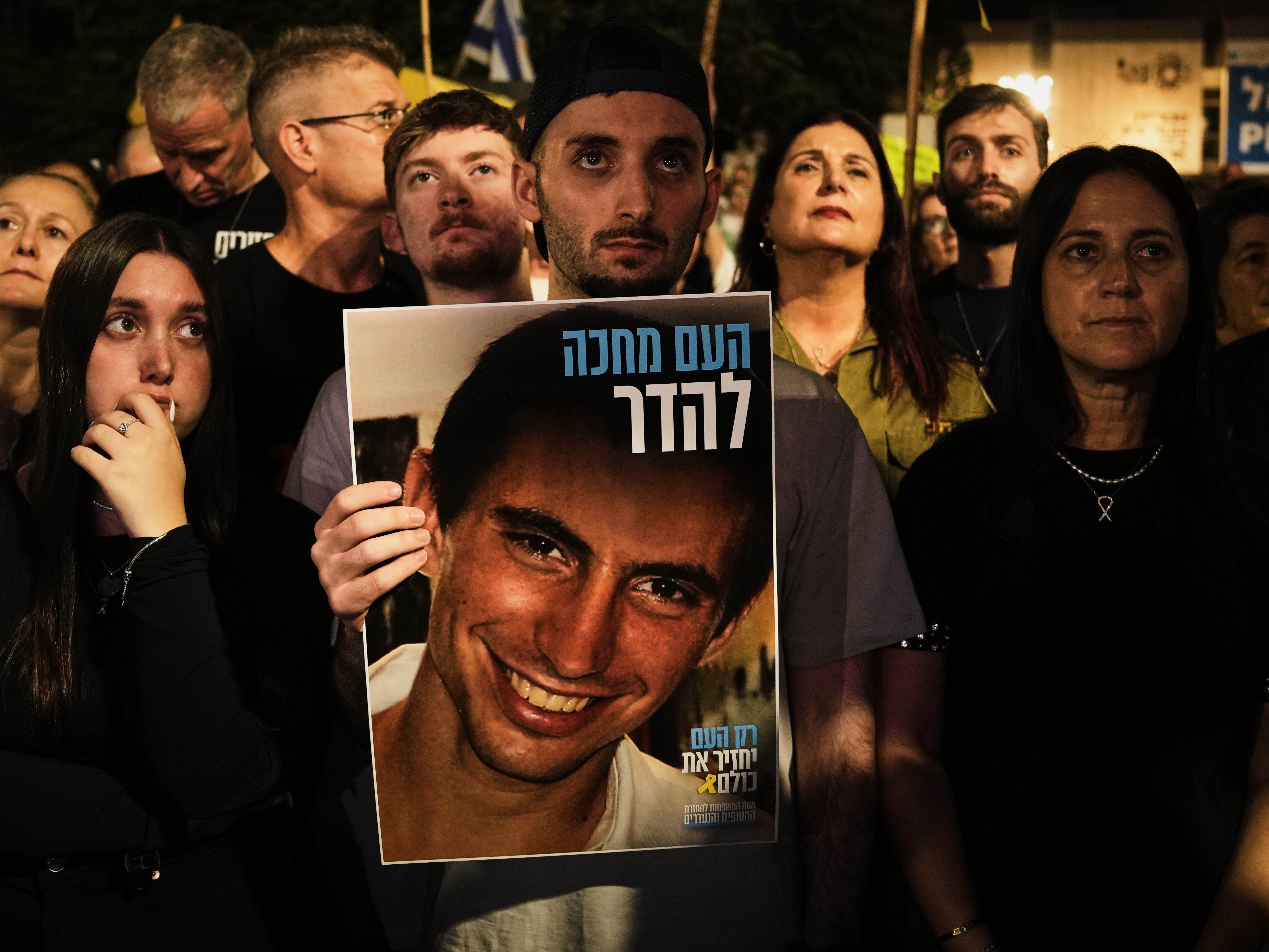caption: Freed Israeli hostage Matan Angrest holds a photo of Hadar Goldin, an Israeli soldier killed in 2014 whose body has been held in Gaza since then, during a rally calling for the return of the deceased hostages who are held by Hamas in the Gaza Strip, in Tel Aviv, Israel, Saturday, Nov. 8, 2025.