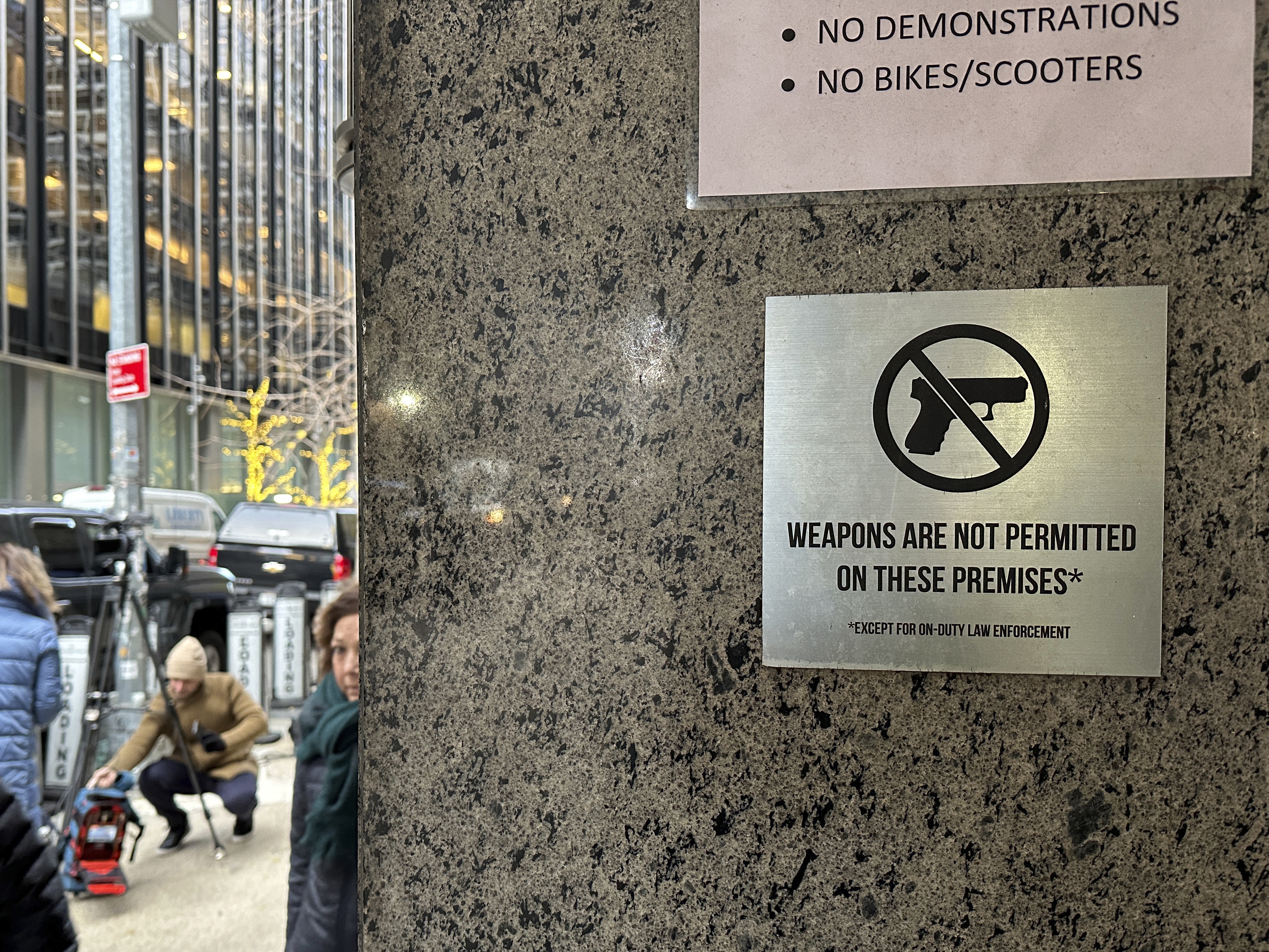 caption: A no guns allowed sign is posted at the 54th Street entrance to the New York Hilton Midtown Hotel in New York, where Brian Thompson, the CEO of UnitedHealthcare, was fatally shot last week.
